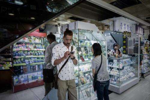 Customers stand outside a shop selling smartphones, in Hong Kong, on September 12, 2014