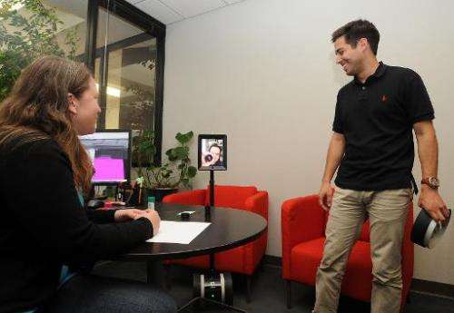 Employees speak with David Cann (C), CEO and Co-founder of Double Robotics, on a Telepresence 'Double' Robot, at the company's h
