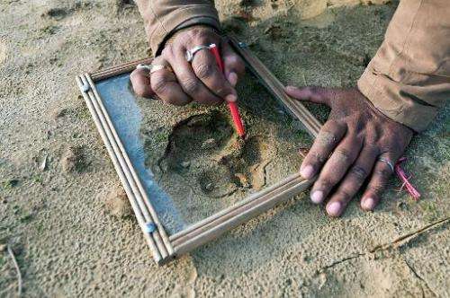 Forest guard Deepak Shukla draws pugmarks on a glass during a tiger hunt in the forest near the village of Barahpur village in B