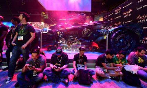 Gaming fans take a break beside the Batman &quot;Arkham Knight&quot; display at the annual E3 video game extravaganza in Los Ang