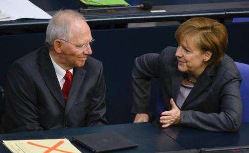 German Finance Minister Wolfgang Schaeuble (L) speaks with German Chancellor Angela Merkel before presenting his draft budget fo