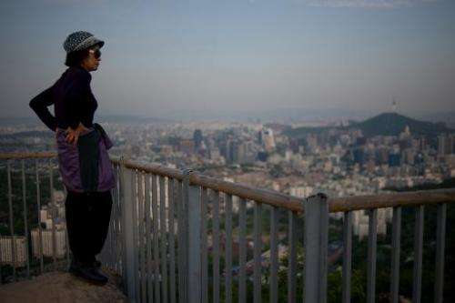 In a photo taken on May 9, 2014, a South Korean woman stands before the Seoul city skyline at dusk