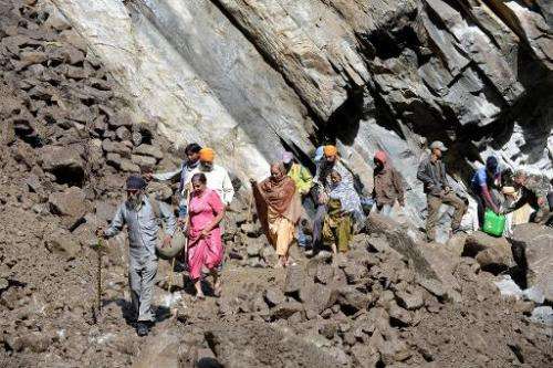 Indian Hindu pilgrims and villagers make their way across a landslide as they walk through Govindghat following flash floods in 