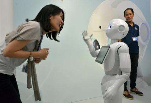 Japanese mobile communication giant Softbank's humanoid robot &quot;Pepper&quot; (R) chatting to a woman at a high-tech gadgets 