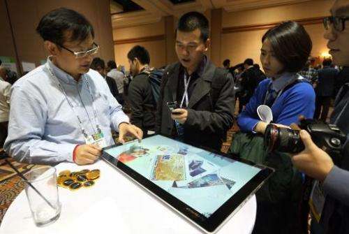 Journalists watch a presentation of Lenovo's new Horizon 2 table PC, a 27-inch, 10-point touchscreen that can be paired to an An