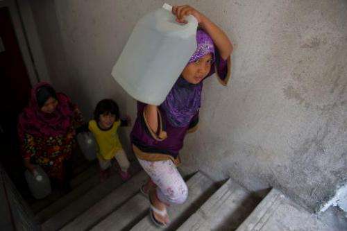 Maisarah Izzati, 12, (R) a daughter of Norlizan, carries a water container in Balakong, outside Kuala Lumpur on February 25, 201