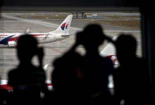 Malaysian children are silhouetted as they watch a Malaysia Airlines (MAS) plane taxi on the runway at Kuala Lumpur Internationa