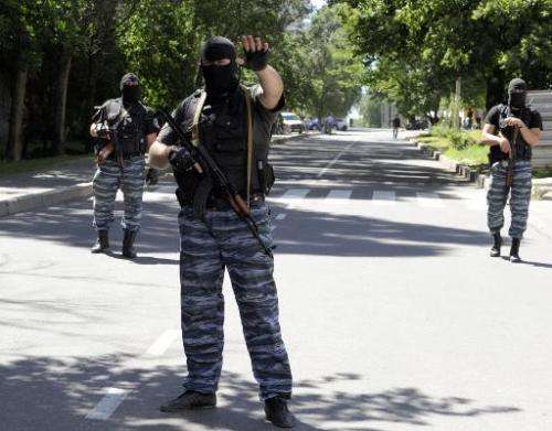 Masked armed men wearing uniforms with the emblem of the Berkut, Ukraine's bisbanded elite riot police force, block the road in 