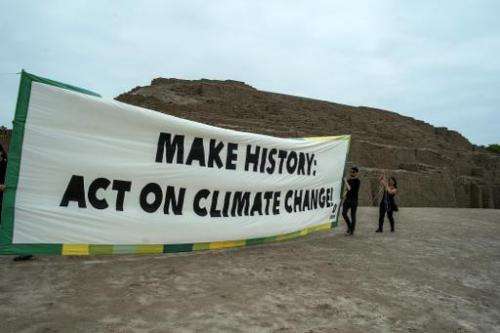 Members of Oxfam international organization hold a banner at the archaeological site of Huaca Pucllana in Lima on November 29, 2