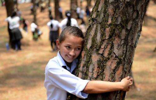 Nepalese school children hug trees in a bid as they celebrate World Environment Day in the forest of Gokarna village, on the out