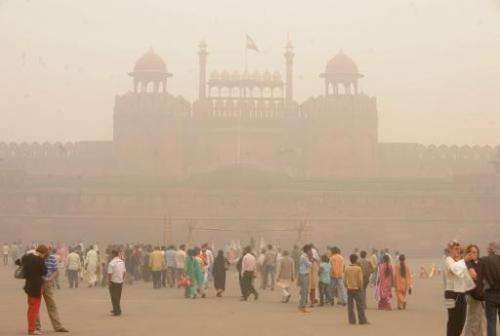 Pedestrians and visitors gather as smog envelopes The Red Fort in New Delhi on November 7, 2009