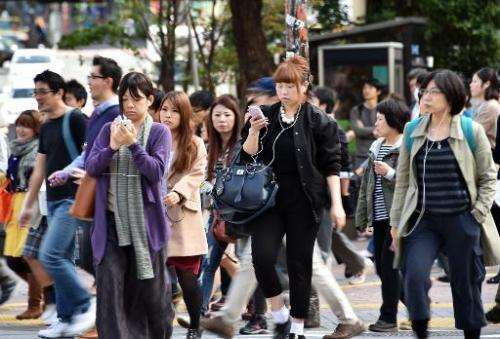 Pedestrians use their smartphones on a street in Tokyo, November 3, 2014. Growing ranks of cellphone addicts are turning cities 