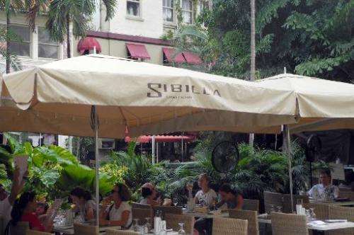 People eat at the terrace of an Italian restaurant in Miami Beach, Florida on October 11, 2011