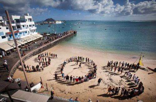 People form a giant S.O.S. on a beach as they protest against oil exploration being carried off the coast of the Canary Islands,