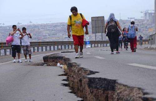 People walk along a cracked road in Iquique, northern Chile, a day after a powerful 8.2-magnitude earthquake hit off Chile's Pac