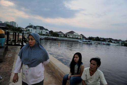 Residents gather along a dyke in Jakarta as construction of the Indonesian capital's sea wall begins, October 9, 2014