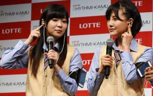 Rino Sashihara (L) and Haruka Kodama, members of pop group HKT48, display Lotte's prototype 'Rhythmi-Kamu', ear phones that coun