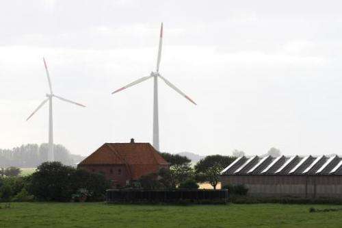 Solar cells are seen along windmills at a farm on the Pellworm island in northern Germany, on August 9, 2013