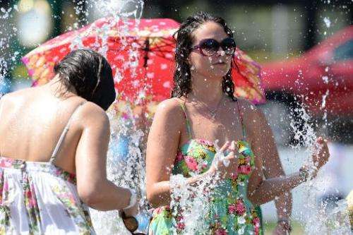 Spectators cool down in a fountain during the hot weather on day two of the 2014 Australian Open tennis tournament in Melbourne 