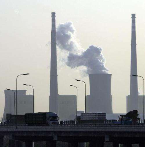 Towering smokestack chimneys and a cooling tower emit steam clouds into the air on November 30, 2006 in Beijing