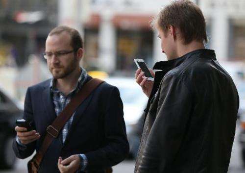 Two pedestrians use smartphones as they walk in Union Square on June 5, 2013 in San Francisco, California
