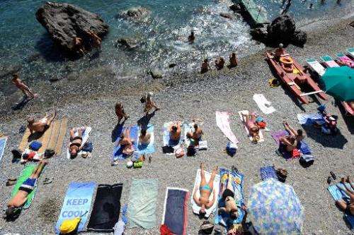 Vacationers swim and sunbathe at a public beach in southern Genova, Italy on August 11, 2011