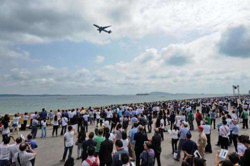 Visitors watch as an Airbus A350 flies past, during the Singapore Airshow, on February 12, 2014