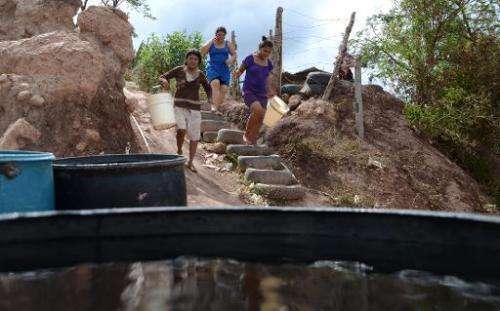 Women walk to collect water after a tanker filled containers in a poor neighbourhood on the outskirts of Tegucigalpa on August 7
