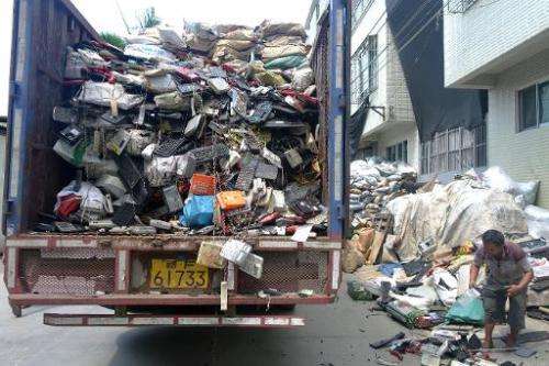 Workers unload a truck carrying electronic waste in Guiyu Township in Shantou City, south China's Guangdong, August 9, 2014