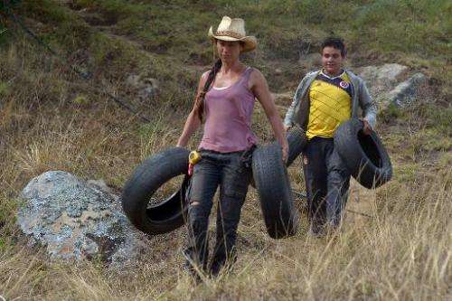 Alexandra Posada (L) carries tires for the roof of her home in Choachi, Colombia on March 16, 2015