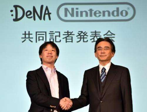 Japan's video game giant Nintendo president Satoru Iwata (right) shakes hands with Japanese online game operator DeNA president 