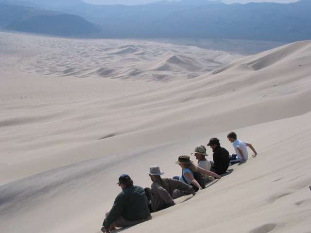 Physics of booming and burping sand dunes revealed