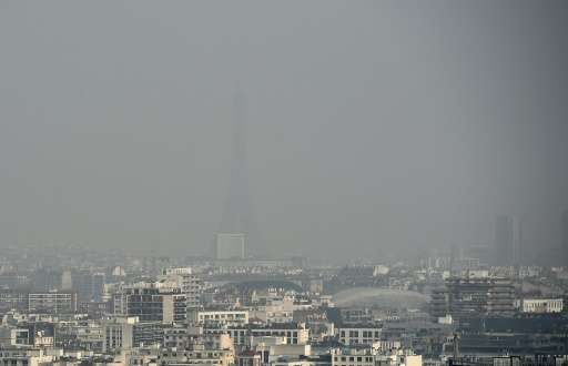 The Eiffel tower and Paris' roofs are seen through a haze of pollution on March 18, 2015