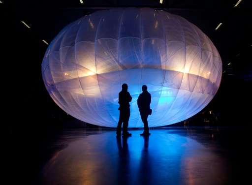 Visitors stand next to a a Google Project Loon balloon, on display at the Airforce Museum in Christchurch on June 16, 2013