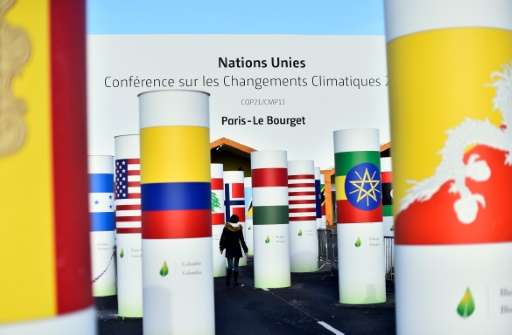 A woman walks past pillars with the  national flags of countries attending the COP 21 UN climate conference, in Le Bourget, nort