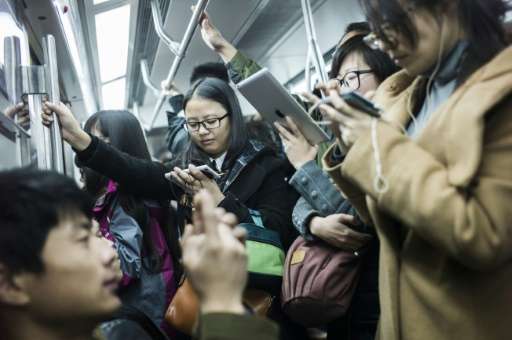 People use their phones in the metro during the morning rush hour in Beijing on November 17, 2014