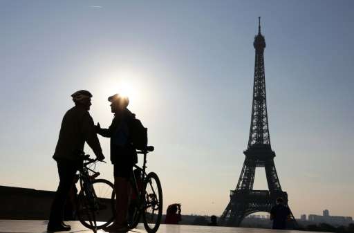 Picture taken early in the morning on September 27, 2015 shows two men with bikes chatting in front of the Eiffel Tower before t