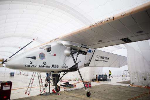 Support crew members stand near the Solar Impulse 2 at Mandalay international airport on March 20, 2015