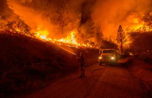 A firefighter douses flames from a backfire while battling the Butte fire near San Andreas, California on September 12, 2015