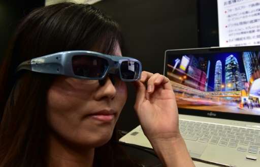 An employee of Japan's computer giant Fujitsu demonstrates a prototype of the 'Retissa' retinal imaging eyewear - which can proj