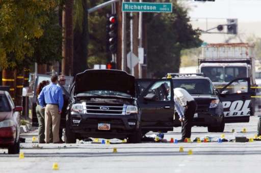 Investigators look at the vehicle involved in a shootout between police and two suspects in San Bernardino, California, on Decem