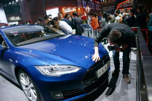 Visitors look at a Tesla car during the 16th Shanghai International Automobile Industry Exhibition in Shanghai on April 24, 2015