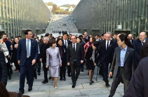 French President Francois Hollande (C) walks around the Ewha Campus Complex, designed by French architect Dominique Perrault, as