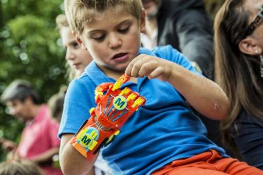 A boy examines his new 3D-printed hand given to him by the Association for the Study and Assistance of Child Amputees on August 