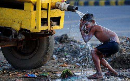 A boy washes himself from a roadside water tanker in Faridabad, a suburb of New Delhi, on March 18, 2015