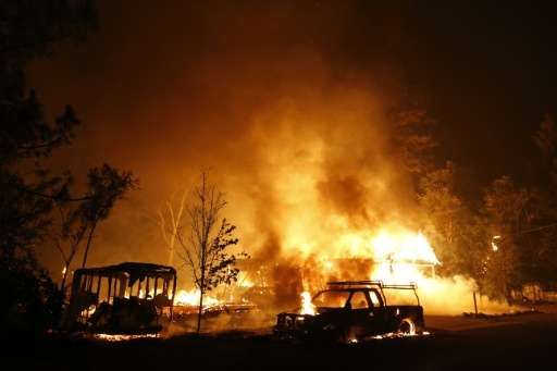 A car burns in front of a burning home during Valley Fire on September 13, 2015 in Middletown, California