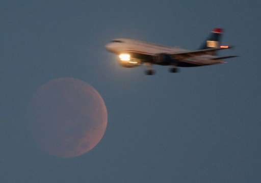 A commercial airliner approaches Reagan National Airport in Washington, DC, as it flies past the full moon during a lunar eclips