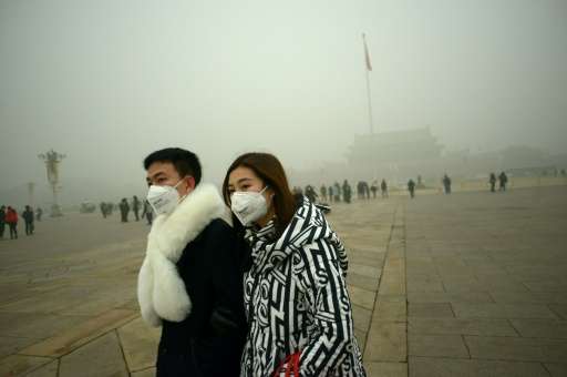 A couple walk through Tiananmen Square in Beijing during a heavy smog on December 1, 2015