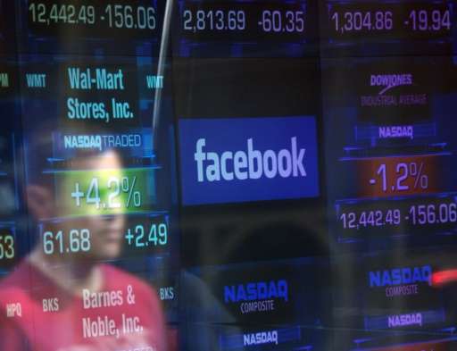 A Facebook logo seen through the windows of the NASDAQ stock exchange as people walk by in New York on May 17, 2012