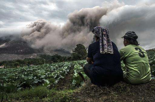 A farming family look on as Mount Sinabung volcano erupts in Karo district, North Sumatra province on June 16, 2015